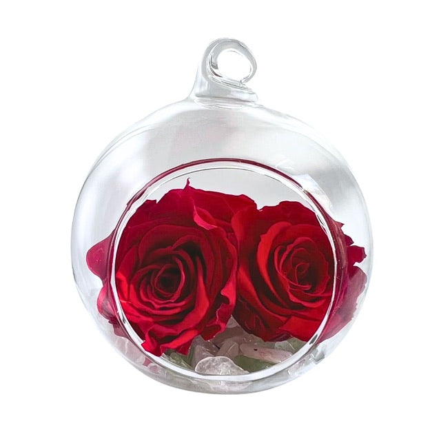 A hanging glass, Blooming Crystal Love Bubble, with layers of rose quartz, green aventurine, selenite and clear quartz crystals topped with red ForeverFloret preserved roses. 