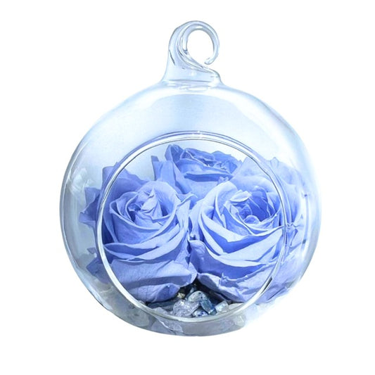 A hanging glass, Blooming Crystal Tranquility Bubble, with layers of celestite, rainbow moonstone, amethyst, selenite and clear quartz crystals, topped with dreamy blue, ForeverFloret preserved roses. 