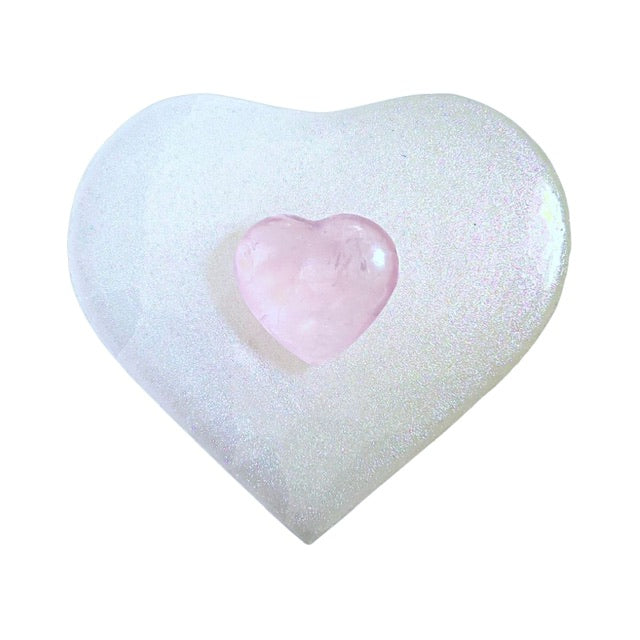 The top view of a pink-shimmery coated selenite heart charging plate with a puffy rose quartz heart in the center. Perfect for crystal lovers and energy enthusiasts."