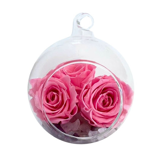 A hanging glass, Blooming Crystal Comfort Bubble, with layers of rose quartz, amethyst, selenite and clear quartz crystals topped with pretty in pink ForeverFloret preserved roses. 