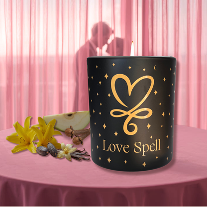 Black Love Spell soy aromatherapy candle with heart design on pink table, surrounded by flowers, vanilla, and spices, with romantic silhouette in soft background.