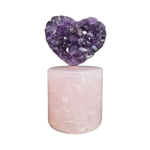 The front view of, a petite amethyst heart crystal, placed atop a rose quartz pedestal. Both unique crystals are from Uruguay.  