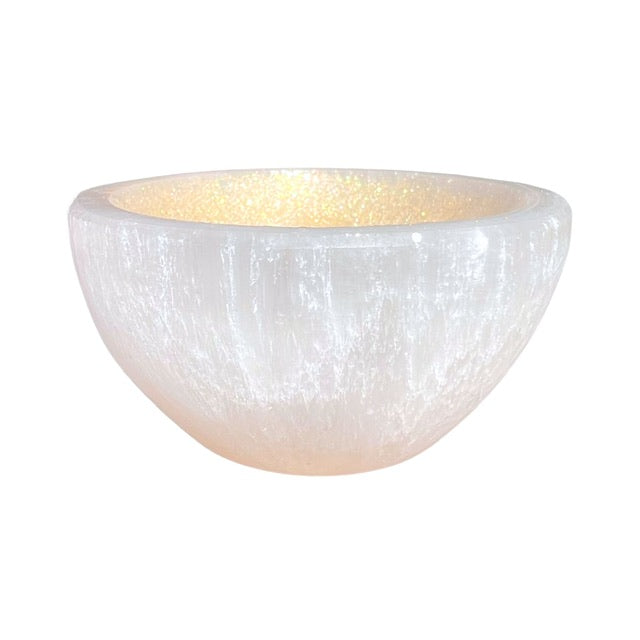A petite selenite crystal bowl, hand adorned with a golden finish.