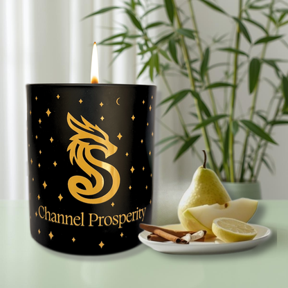 Black prosperity candle with gold dragon design, pear, lemon, and cinnamon sticks on a table.